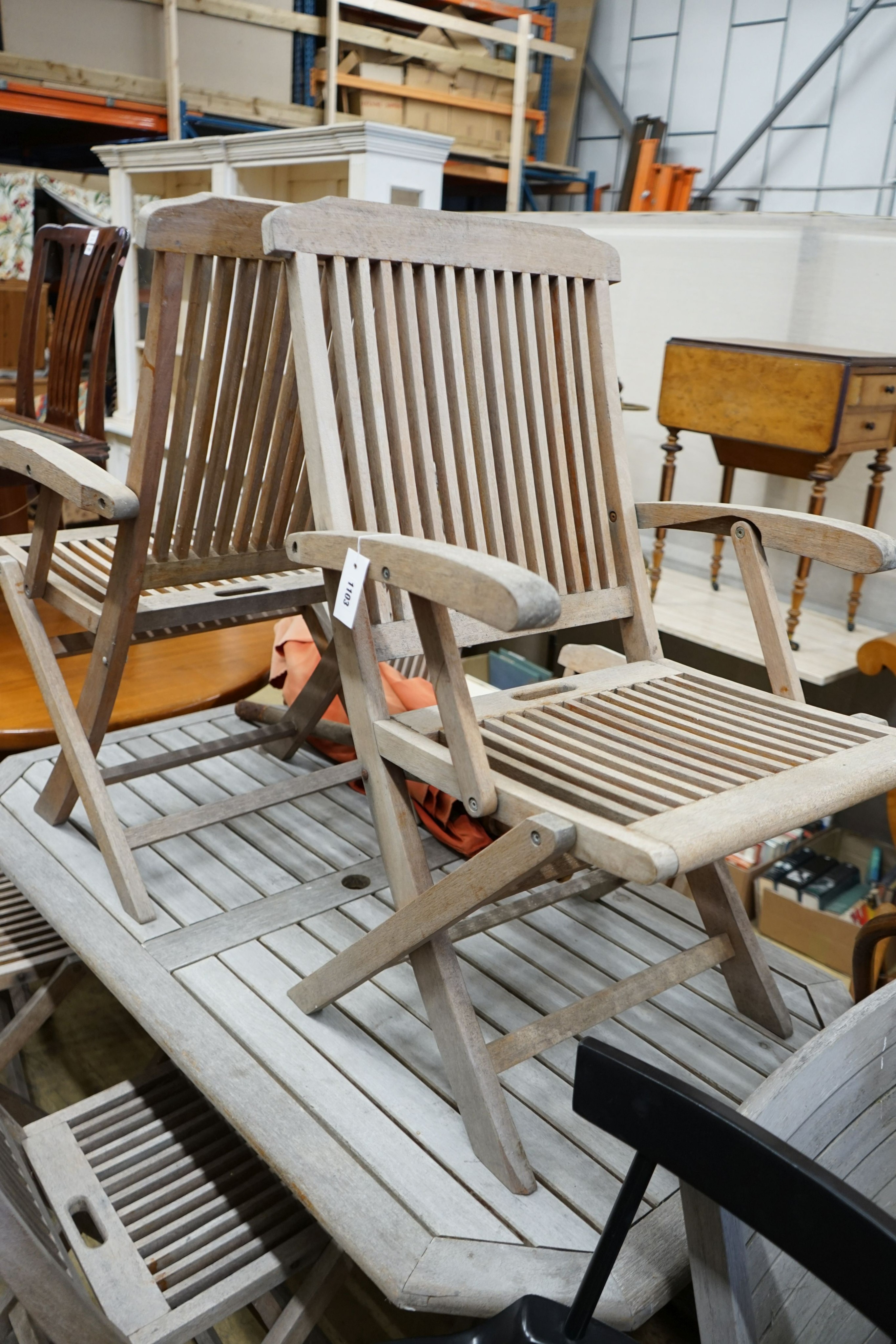 A rectangular weathered teak slatted garden table, length 150cm, depth 79cm, height 72cm, six teak folding chairs, two with arms, parasol and base